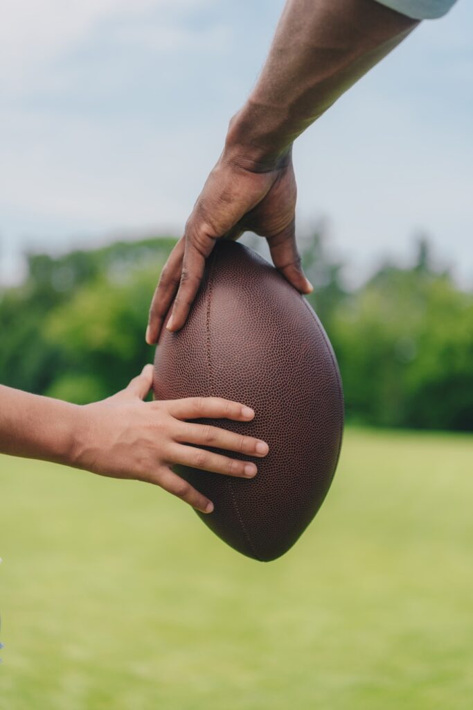 partial view of father and daughter holding football together